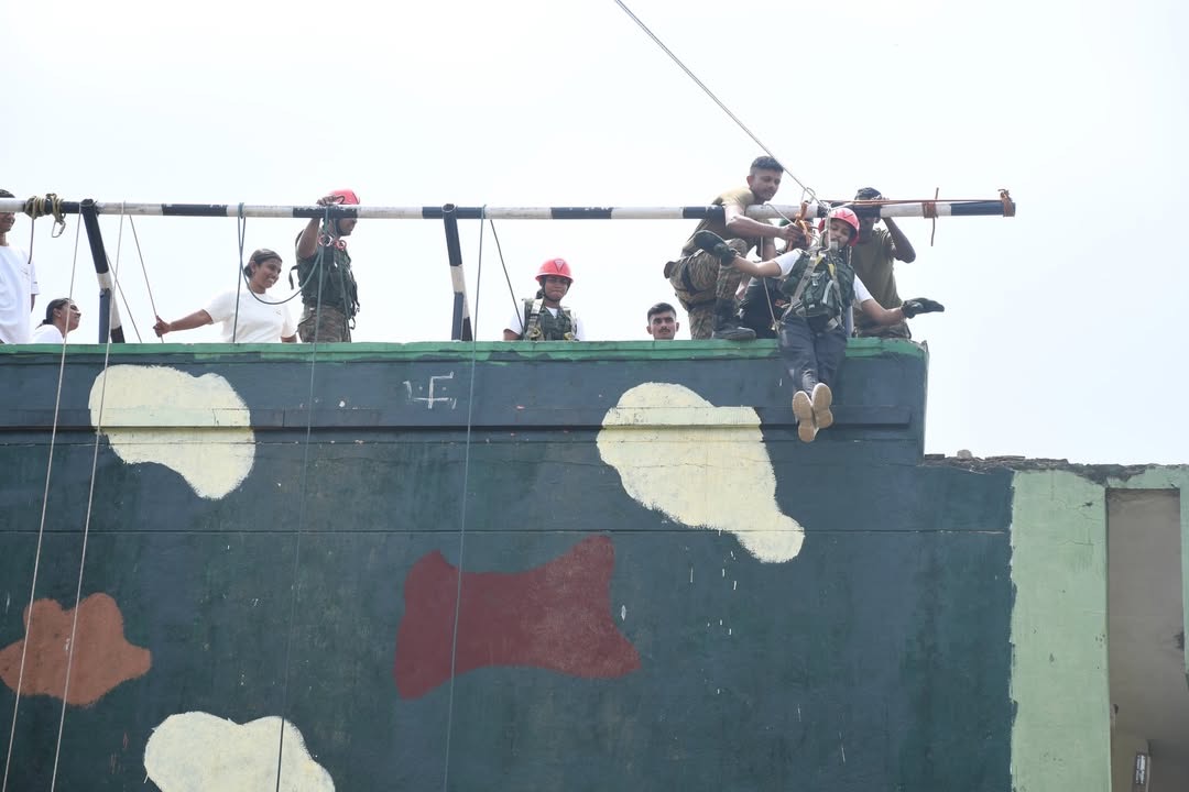 Students helping each other over a climbing wall